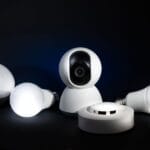10 zaawansowanych automatyzacji Smart Home, które warto wdrożyć po opanowaniu podstaw systemu Zestaw urządzeń smart home: żarówki i kamery na ciemnym tle