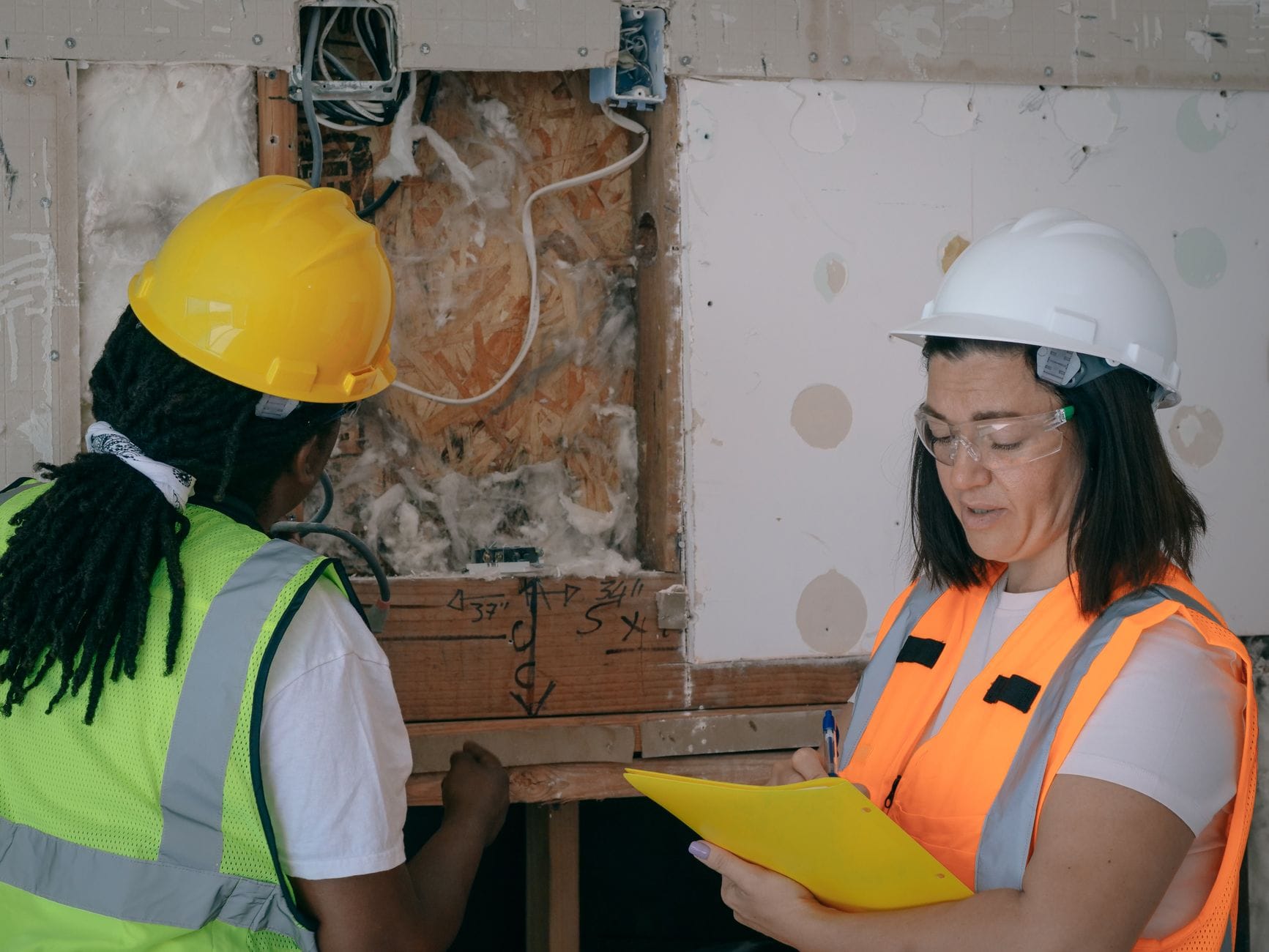 Elektrycy w odzieży ochronnej sprawdzają instalację na budowie