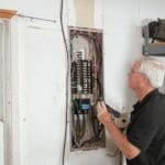 Najczęstsze błędy w domowych instalacjach elektrycznych i jak ich uniknąć Elektryk sprawdza domową rozdzielnicę, dbając o bezpieczeństwo instalacji